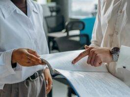 colleagues standing in white long sleeve shirts discussing and reading a financial report