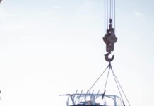 people transporting a boat on crane on rocky coast