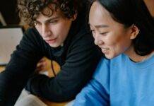 students studying together while looking at the screen of a laptop