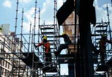 a person in orange long sleeve shirt standing on gray scaffolding