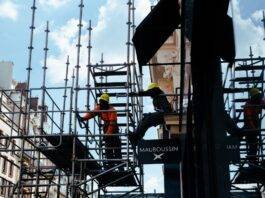 a person in orange long sleeve shirt standing on gray scaffolding