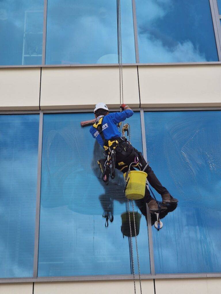 a man cleaning the windows of a skyscraper on a high floor