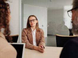 woman in brown blazer seated beside table