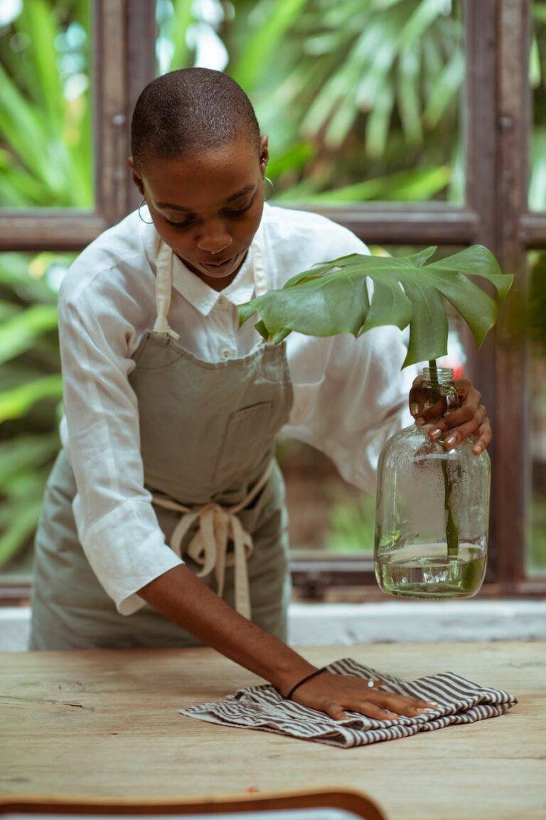 focused housewife in apron cleaning wooden table