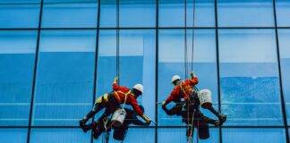 men hanging in ropes cleaning the building glass windows