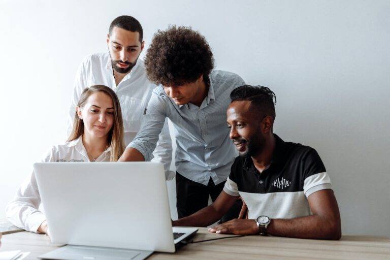a group of people having a discussion while looking at laptop