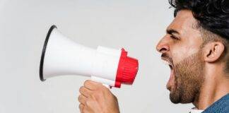 man in blue denim jacket holding a megaphone