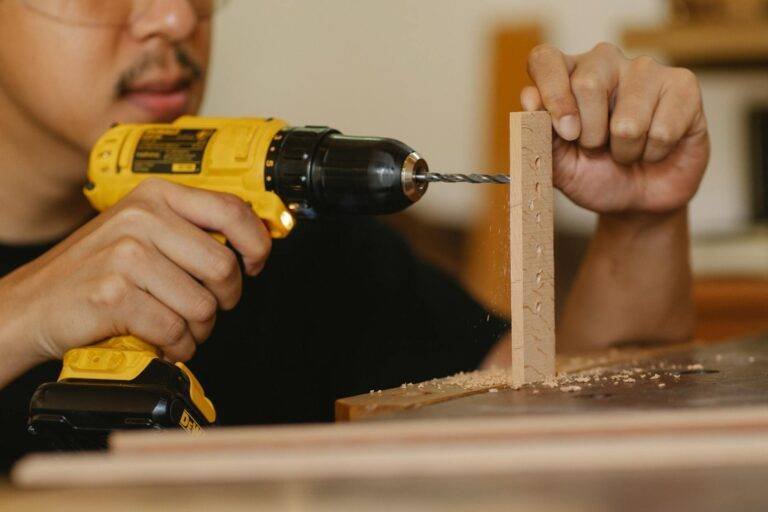 man drilling timber panel with screwdriver on table