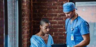 doctor demonstrating diagnosis to pensive black patient in corridor of hospital