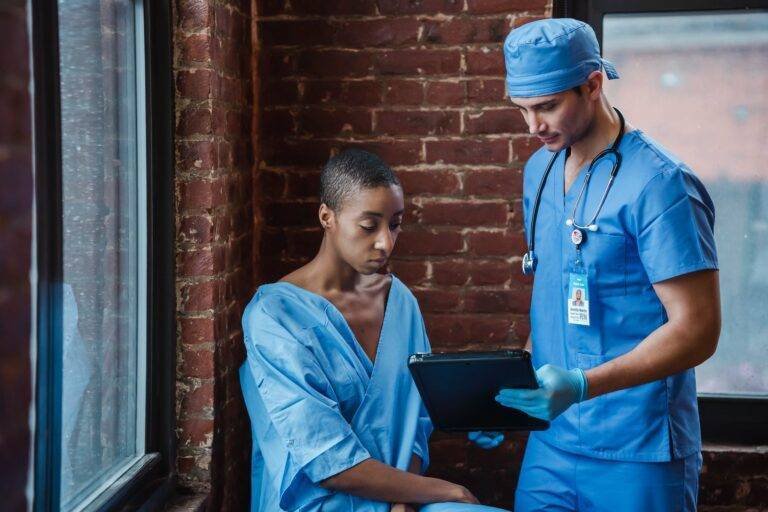 doctor demonstrating diagnosis to pensive black patient in corridor of hospital