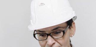 elegant woman wearing a construction helmet and writing in a notepad