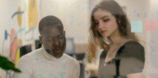man and woman writing with pen on glass in office