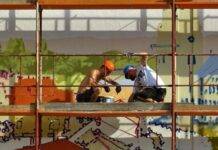 two person on scaffolding painting wall