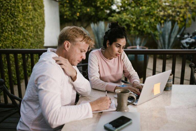 a man and woman sitting at the porch while working together