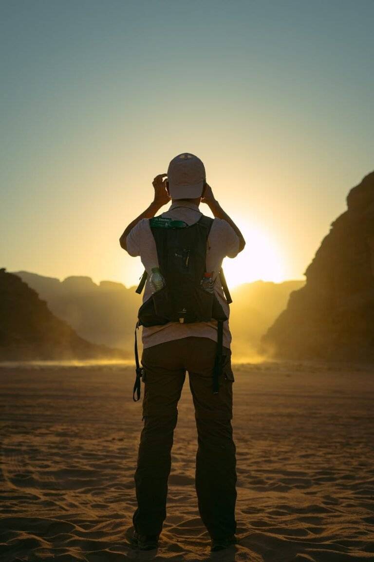back view of man hiking on desert at sunset
