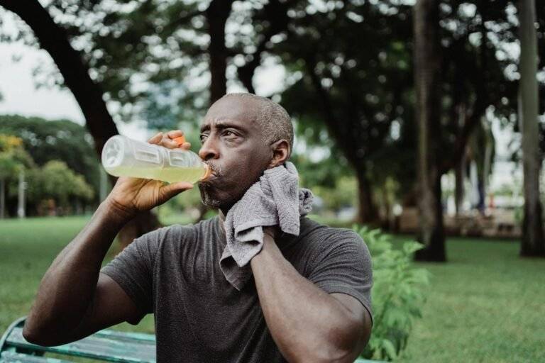 man in black crew neck t shirt drinking yellow liquid from plastic bottle