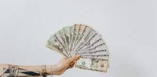 hand holding fan of us dollar bills
