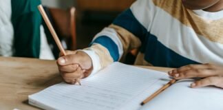 anonymous black pupil solving task during lesson in classroom