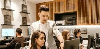 man teaching woman in front of monitor