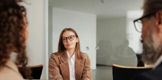 woman in brown blazer seated beside table
