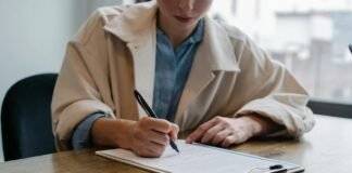 focused woman writing in clipboard while hiring candidate