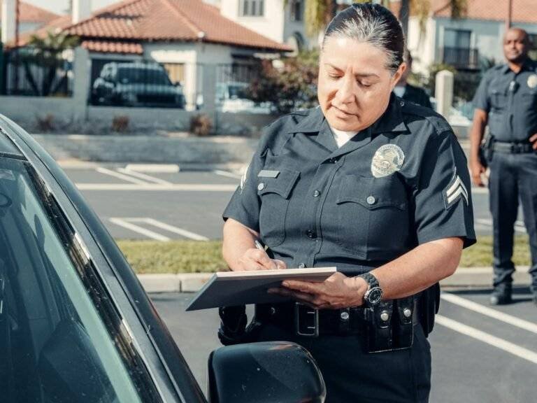 a police officer standing beside a car while holding a clipboard