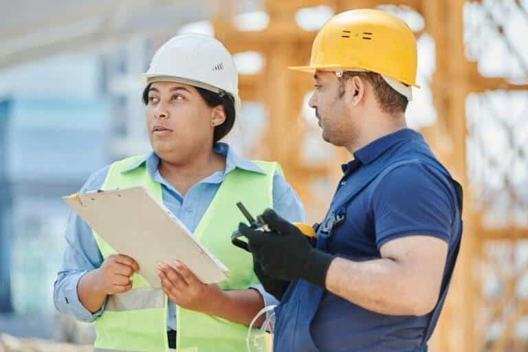 woman in blue long sleeve shirt wearing white hard hat holding white clipboard