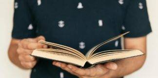 faceless man in tee shirt paging interesting book