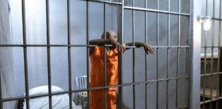 man in orange uniform standing beside gray metal gate