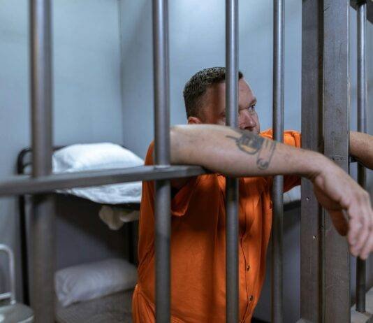 man in orange button up shirt standing beside gray metal bars