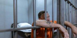 man in orange button up shirt standing beside gray metal bars