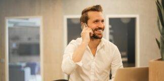 smiling formal male with laptop chatting via phone