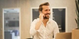 smiling formal male with laptop chatting via phone