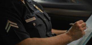 person wearing police uniform writing on a notebook