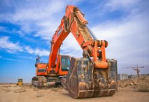 low angle photography of orange excavator under white clouds