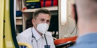 paramedic wearing face mask sitting in the back of an ambulance