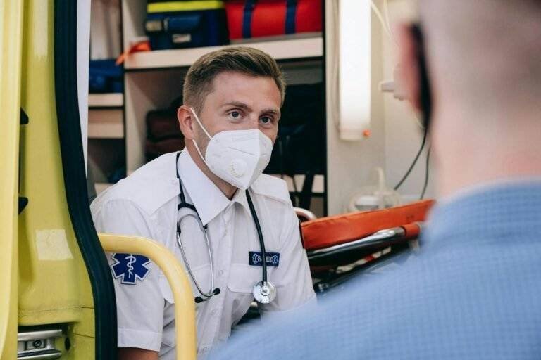 paramedic wearing face mask sitting in the back of an ambulance