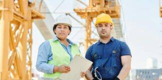 man in blue shirt wearing yellow hard hat standing beside a woman in blue long sleeve shirt