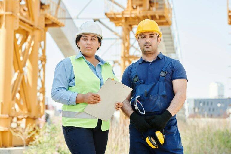 man in blue shirt wearing yellow hard hat standing beside a woman in blue long sleeve shirt