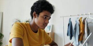 man in yellow crew neck t shirt while using tablet