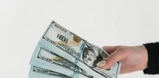 close up shot of a person holding stack of dollar bills