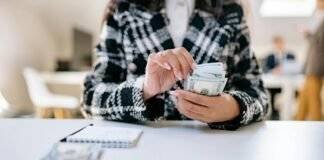 a person in black and white plaid jacket holding banknotes