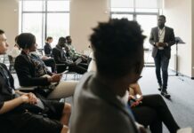 people sitting on the chair listening to the man speaking inside the conference room