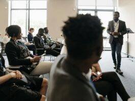 people sitting on the chair listening to the man speaking inside the conference room
