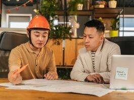 construction worker and an office worker looking at papers together in an office