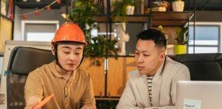 construction worker and an office worker looking at papers together in an office