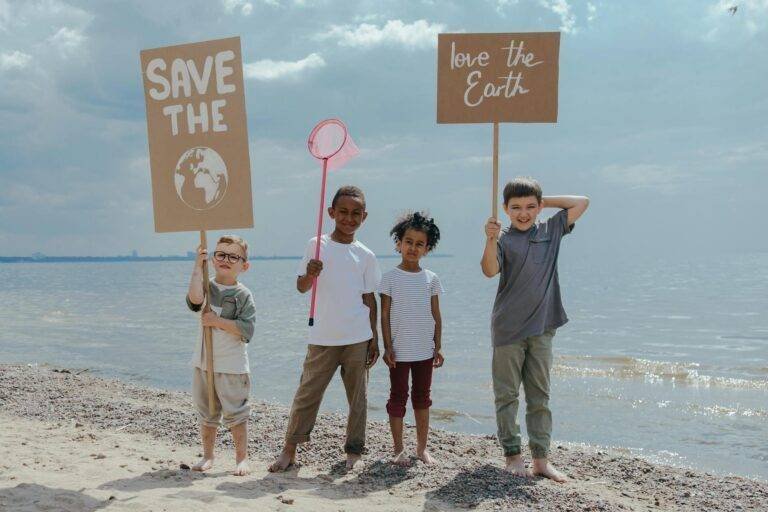 children standing at the seashore while holding signages