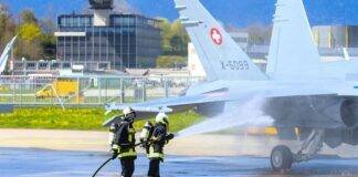 firefighters using water hose on a military airplane