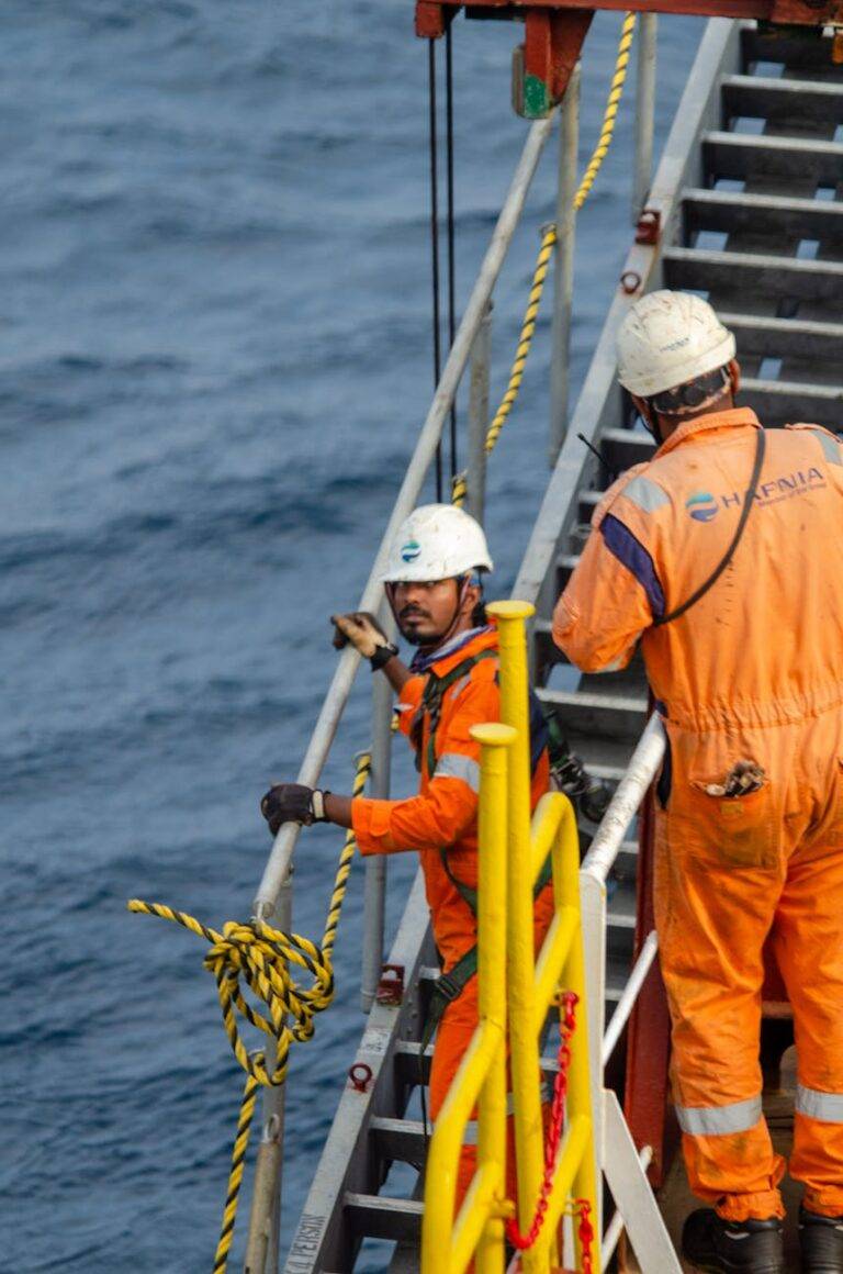 offshore workers in orange safety gear on a ship