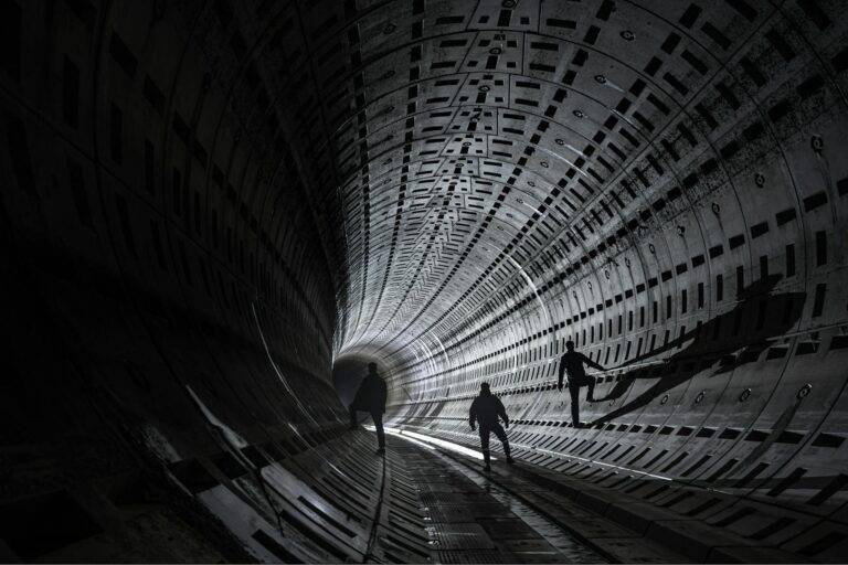 silhouetted explorers in an illuminated tunnel